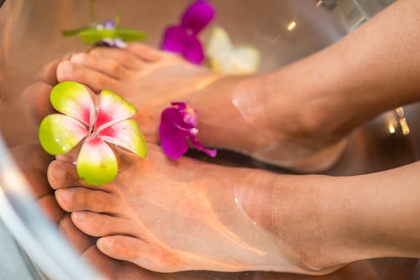 person's feet in water with flowers floating